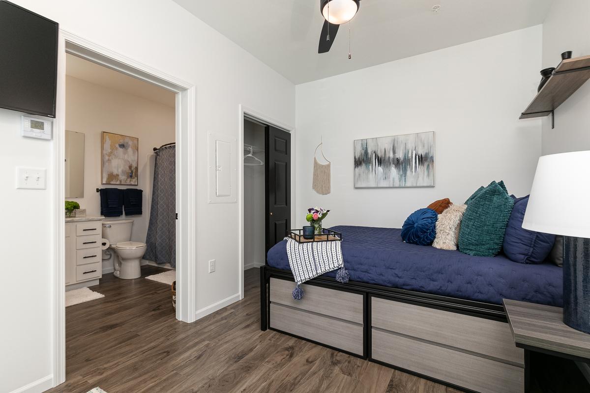 Sleeping nook with the bathroom beyond: navy bedding, television, wall art