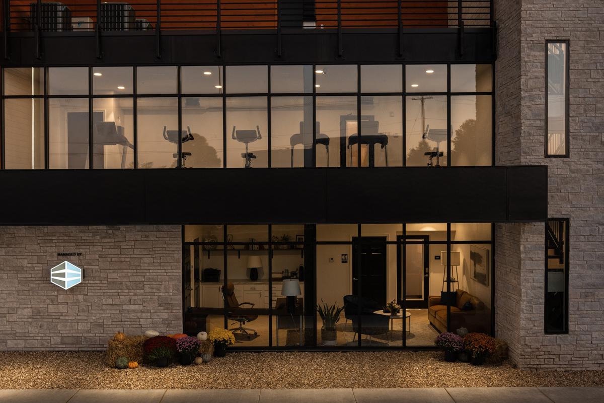 Ground-floor glass front at dusk with the fitness center and lobby lit inside