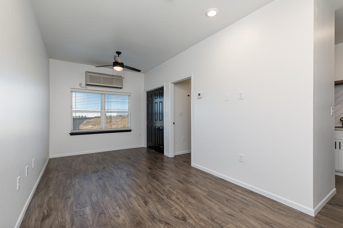 Vacant living area with ceiling fan, window and black doors