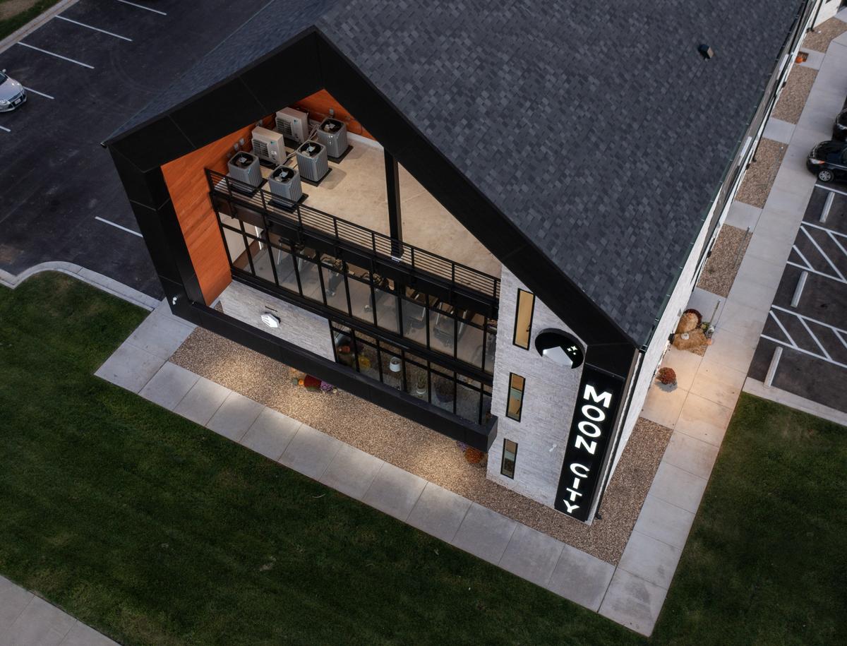 Top-down drone view of the entrance, lawn and sign at dusk