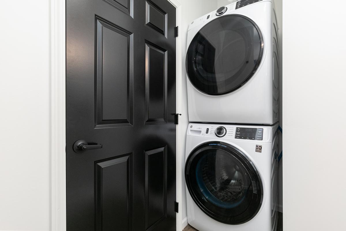 Stacked washer and dryer in a closet with black doors