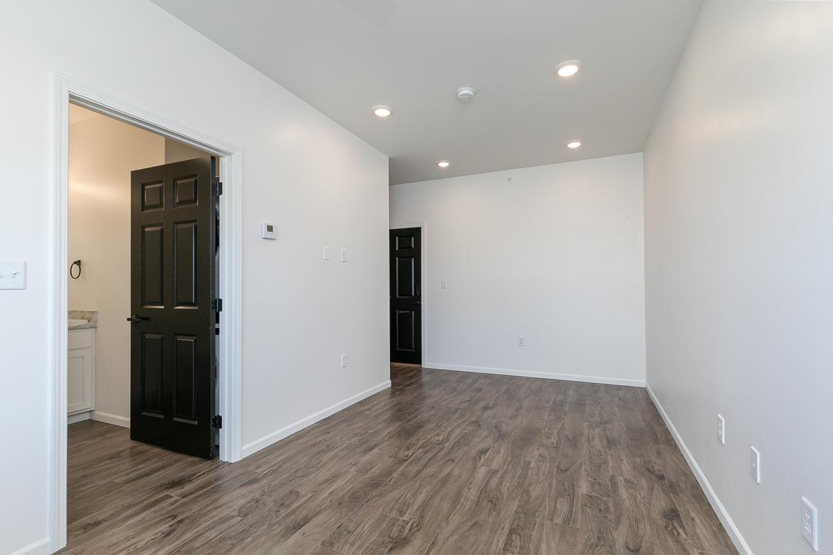 Vacant living area with black doors to the bathroom and closet, wood-look floor