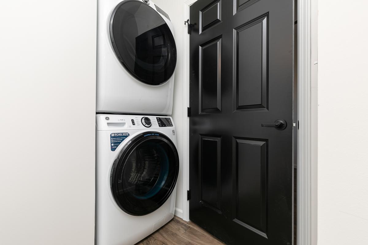Vacant stacked washer and dryer beside the black front door
