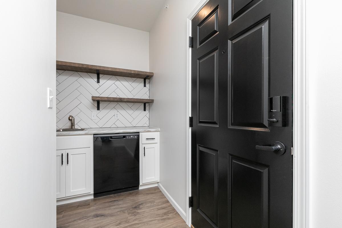 Entry hall with black front door and the kitchen beyond
