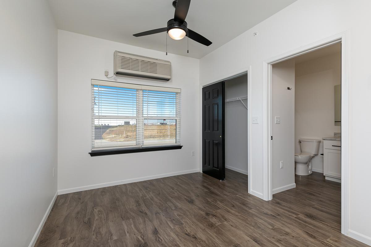 Vacant sleeping area: window, wall unit, open closet and bathroom door