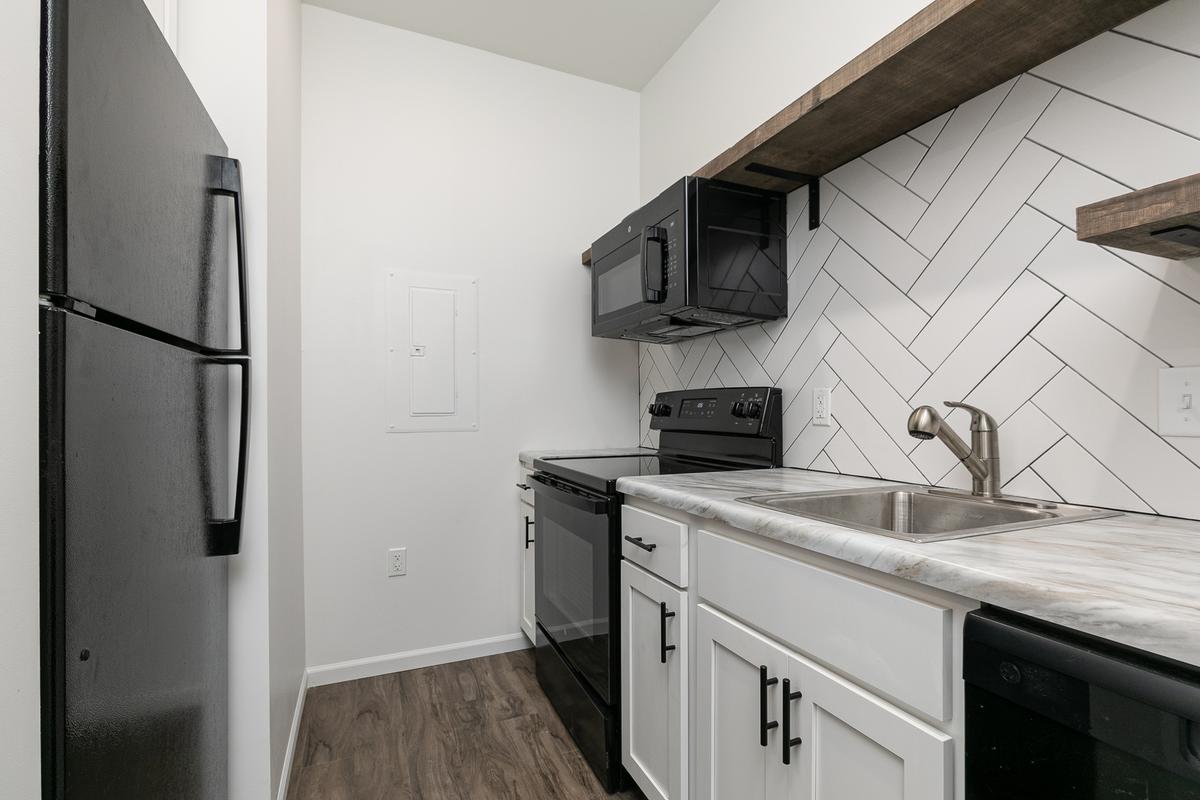 Vacant kitchen with black refrigerator, range and open shelving