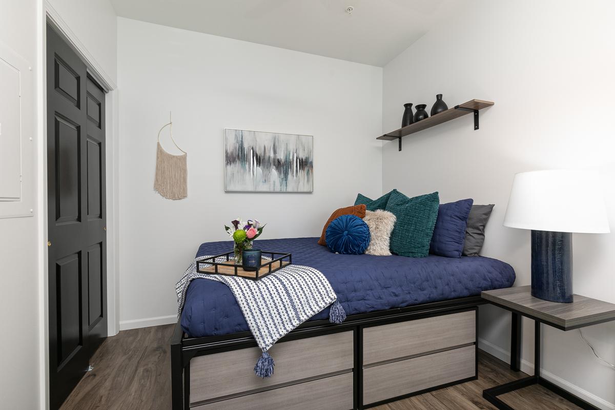 Sleeping nook: platform bed with drawers, navy bedding, wall shelf, lamp