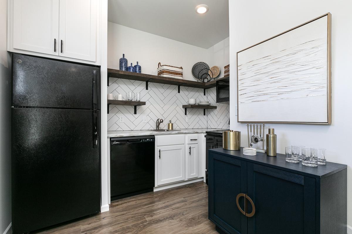 Kitchen: white cabinets, black appliances, open shelving, navy sideboard, abstract wall art